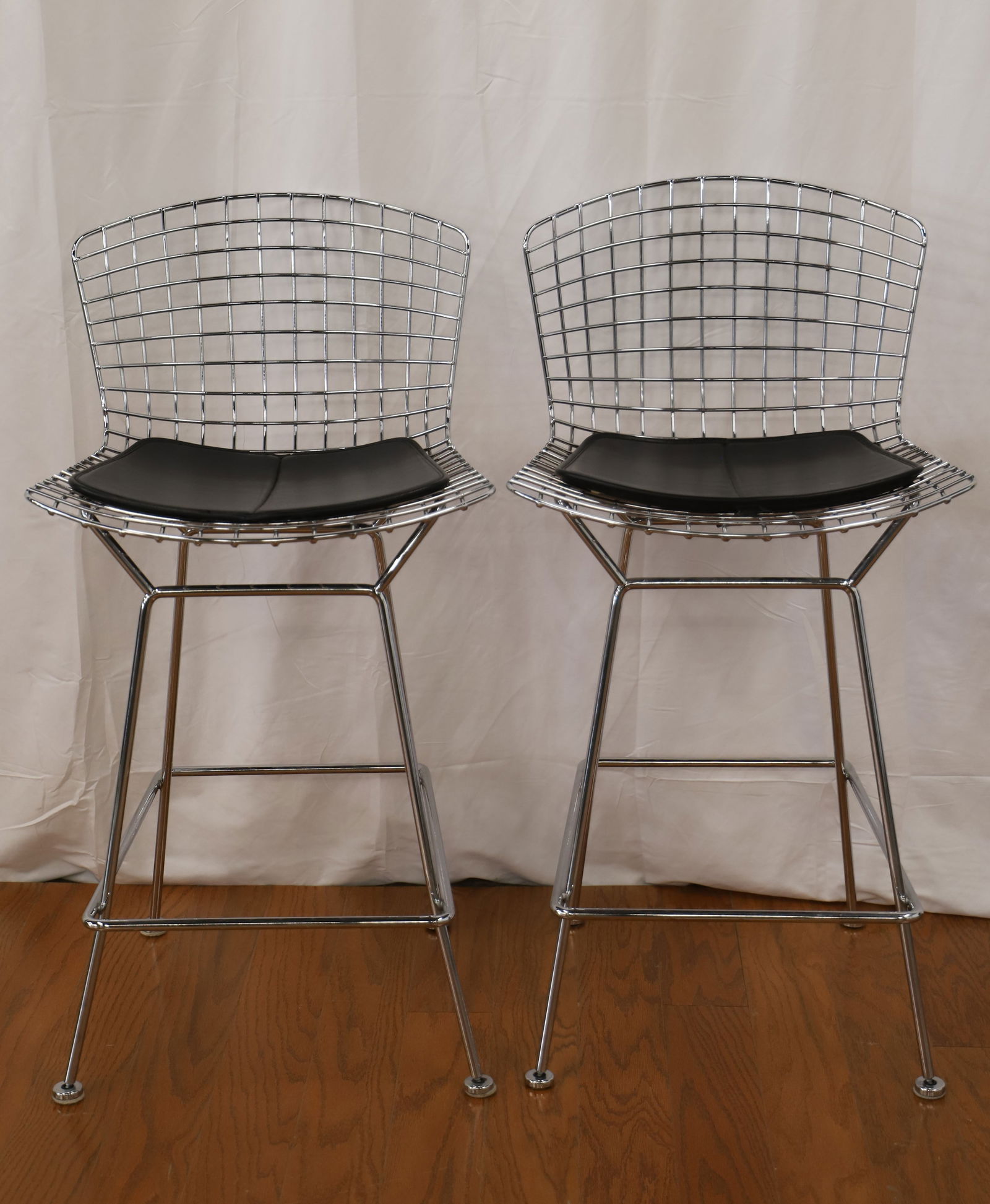 Knoll, Harry Bertoia, Bar Stools: Two vintage chrome bar stools by Knoll for Harry Bertoia; Leather seat pads; Measures approximately H 39 x W 21 x D 25 inches; Discoloration and rust present under the seat pad and in areas on the bas