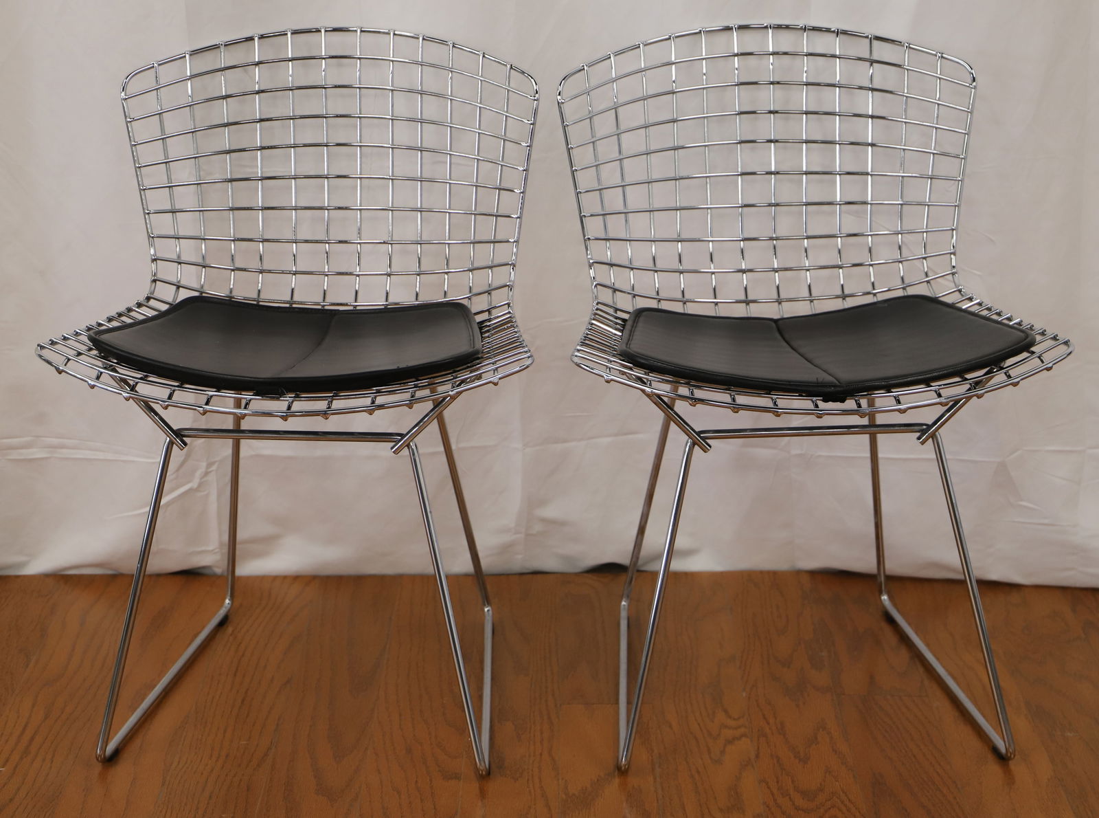 Knoll, Harry Bertoia, Side Chairs: Two vintage chrome side chairs by Knoll for Harry Bertoia; Leather seat pads; Measures approximately H 29 x W 21 x D 21 inches; Mark observed on one seat pad, discoloration and rust present under the