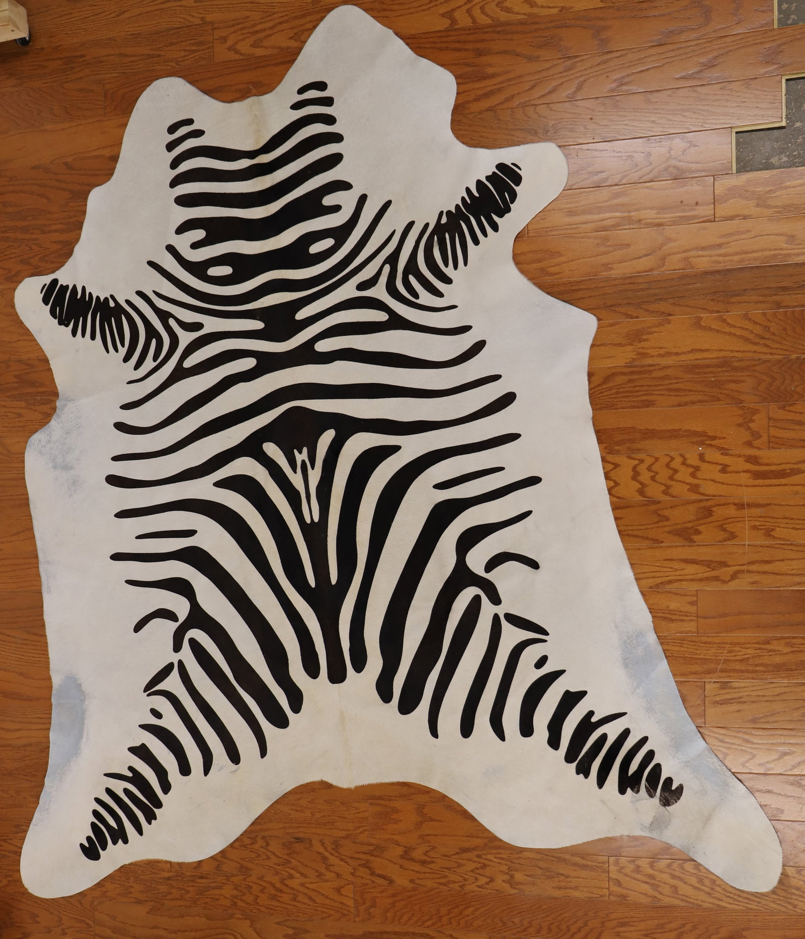 Cow Hide Rug: Cow hide rug with zebra stripes; Marked "Made in Brazil"; Measures approximately W 92 x D 81 inches; Hair is rubbed off in areas, tape reside on the bottom, it has been patched in areas, stains on the