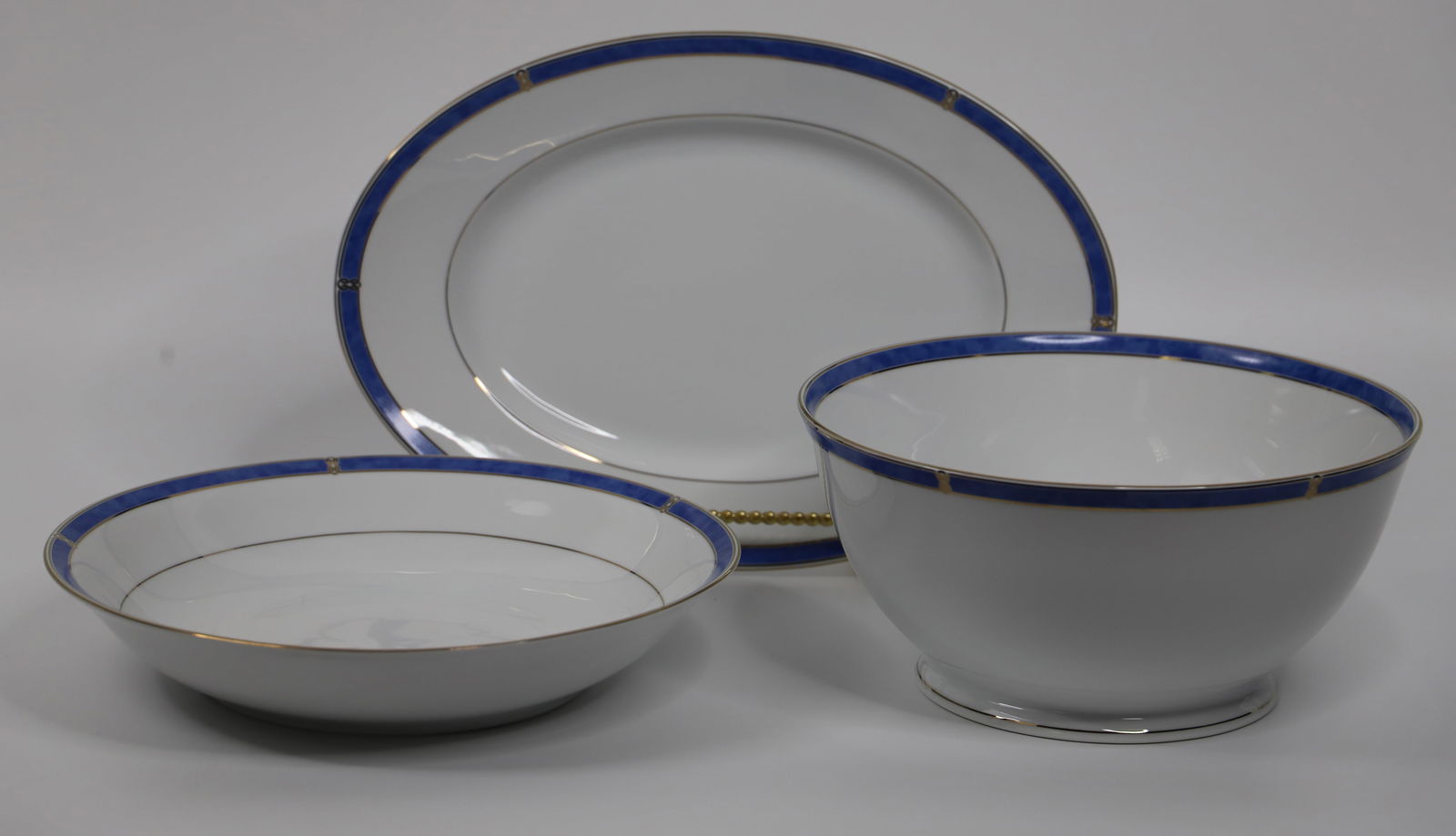 Christofle Porcelain, Serving Pieces: Oval platter and two round serving bowls; All in the "Micro Gold Oceana Bleu" pattern; Tallest bowl measures approximately H 4 3/4 x Diameter 10 inches; No damage observed. See photos