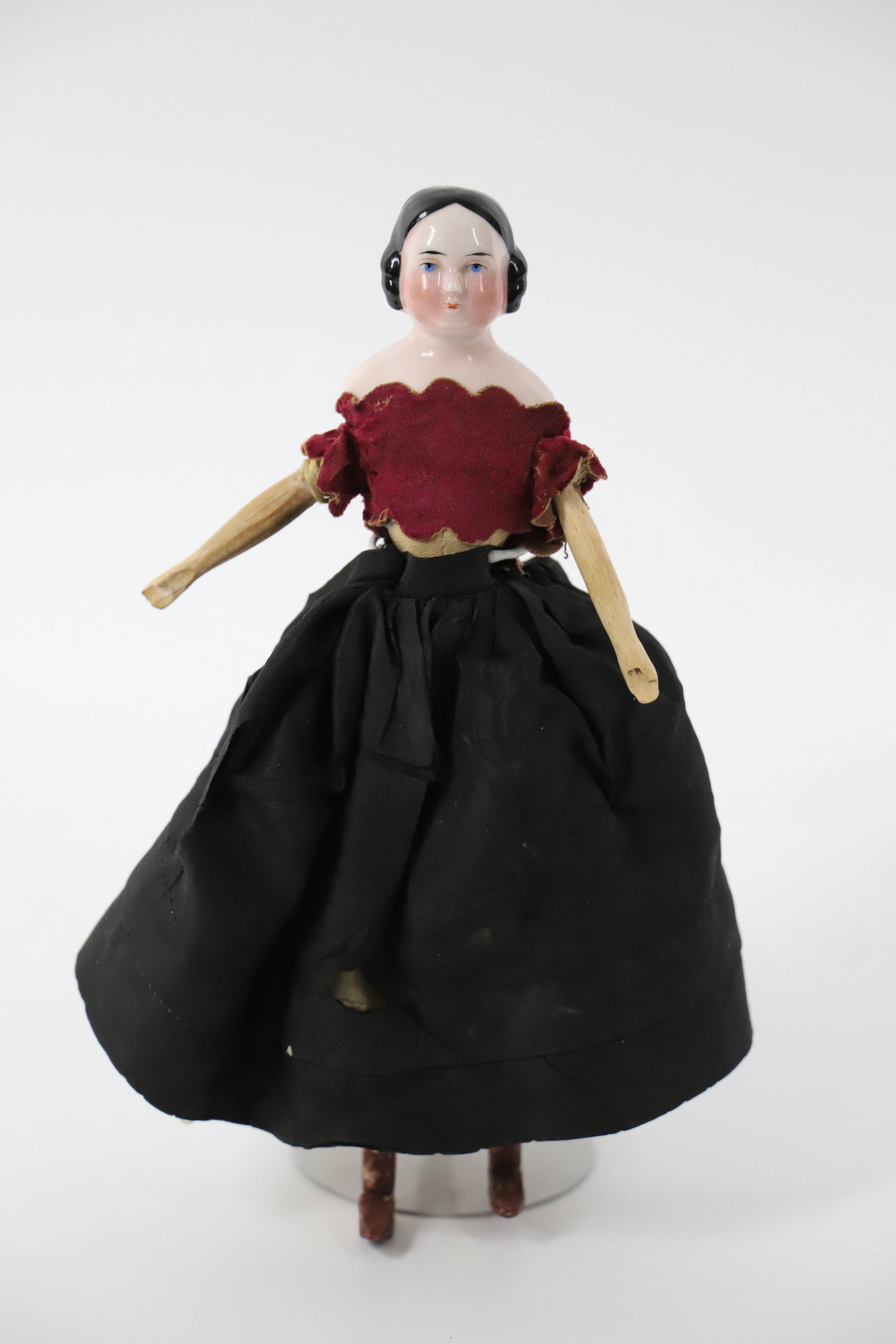 China Head, Wood Doll: Possibly antique china head doll with cloth body and wooden limbs; Measures approximately H 10 x W 6 x D 3 inches; Glaze worn off on the back of the head, paint scratched in areas on the wood, rips in