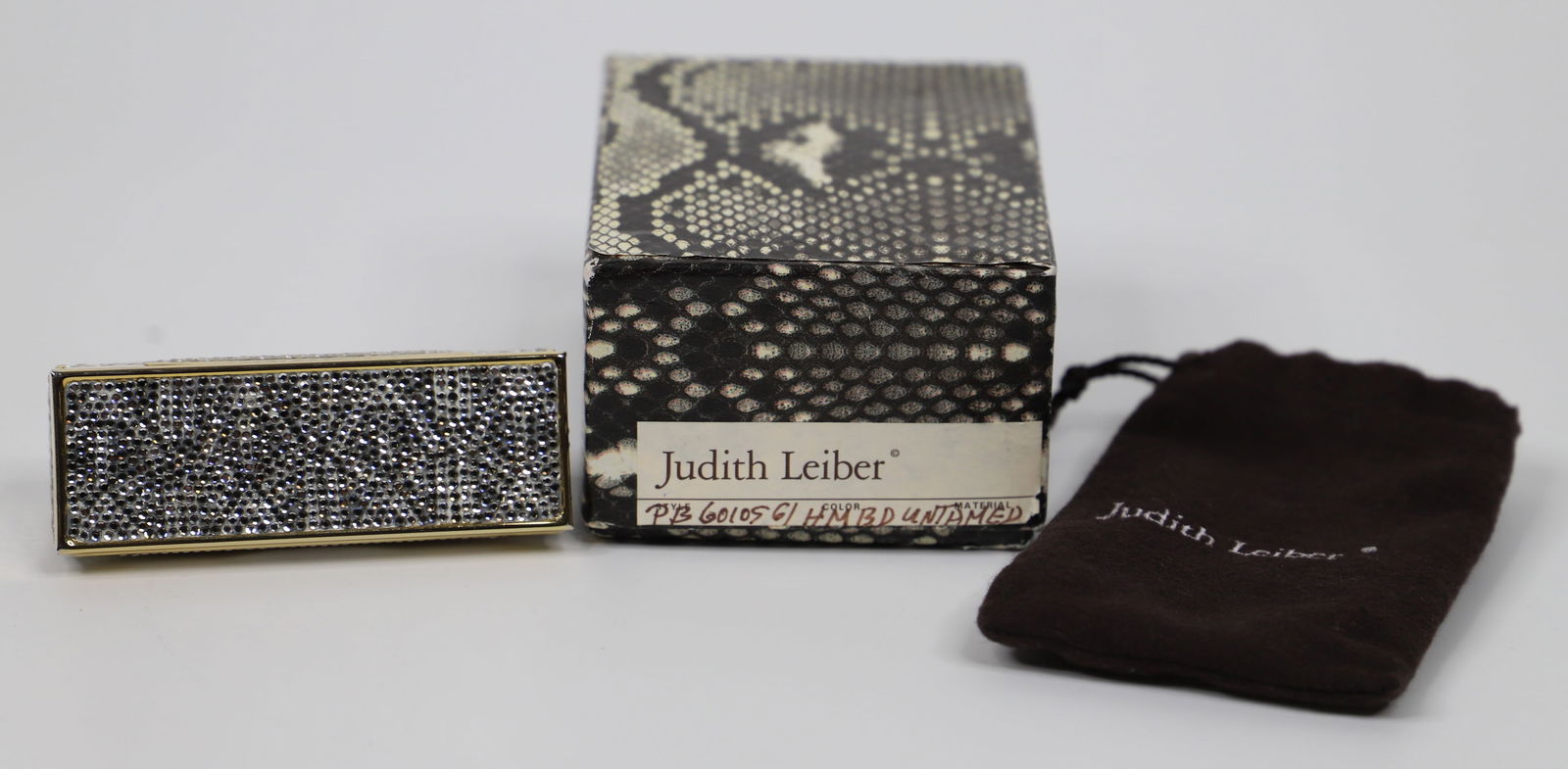 Judith Leiber, Lipstick Case: Judith Leiber jeweled lipstick mirror case with dust bag; Possibly Swarovski crystals; Measures approximately H 1 1/2 x W 3 1/2 x D 1 1/2 inches; Some jewels loose in areas, some jewels missing on one