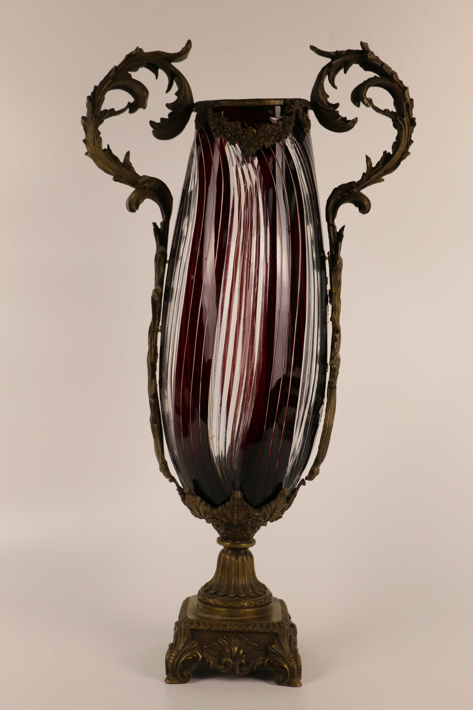 Sculptured Bronze Crystal Vase: Cut ruby and clear crystal vase in possibly bronze base with scroll handles; No maker marks observed; Measures approximately H 21 x W 11 x D 5 1/2 inches; Handles have come unglued/detached from the v