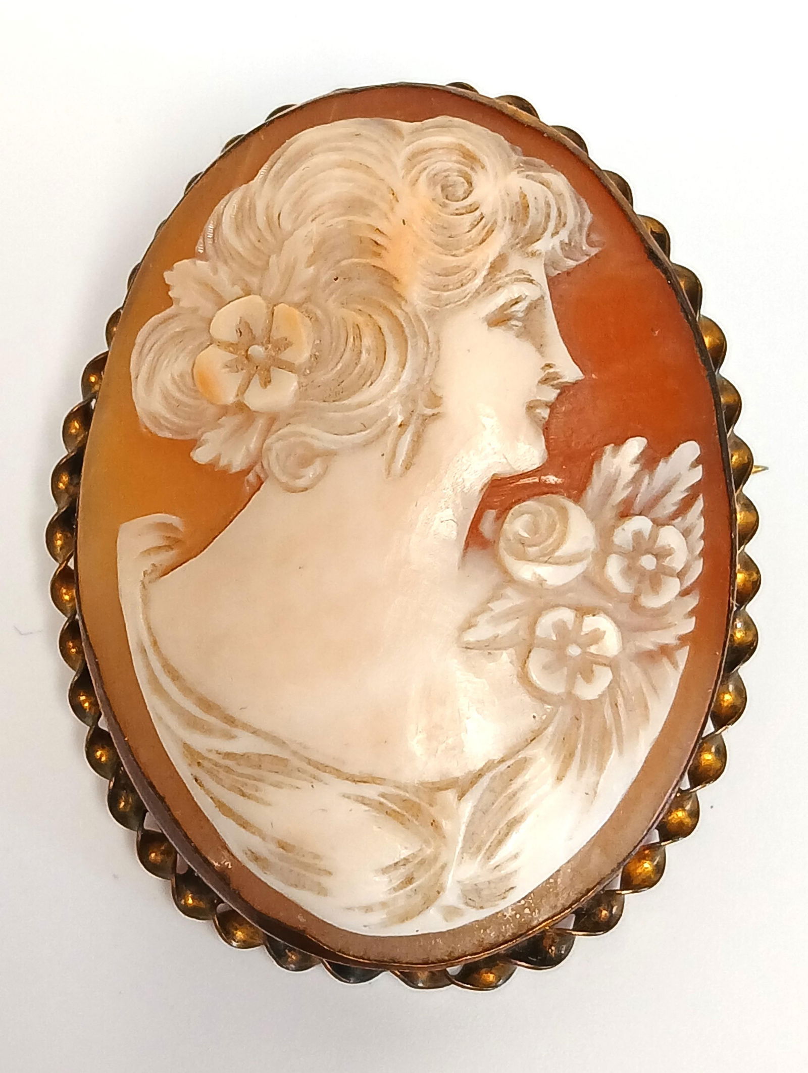 Antique Cameo Brooch: One antique brooch with gold-toned metal frame and hand carved shell cameo; No maker marks observed; Measures approximately H 1 3/4 x W 1 1/2 inches; Brooch has age appropriate wear and some bending t
