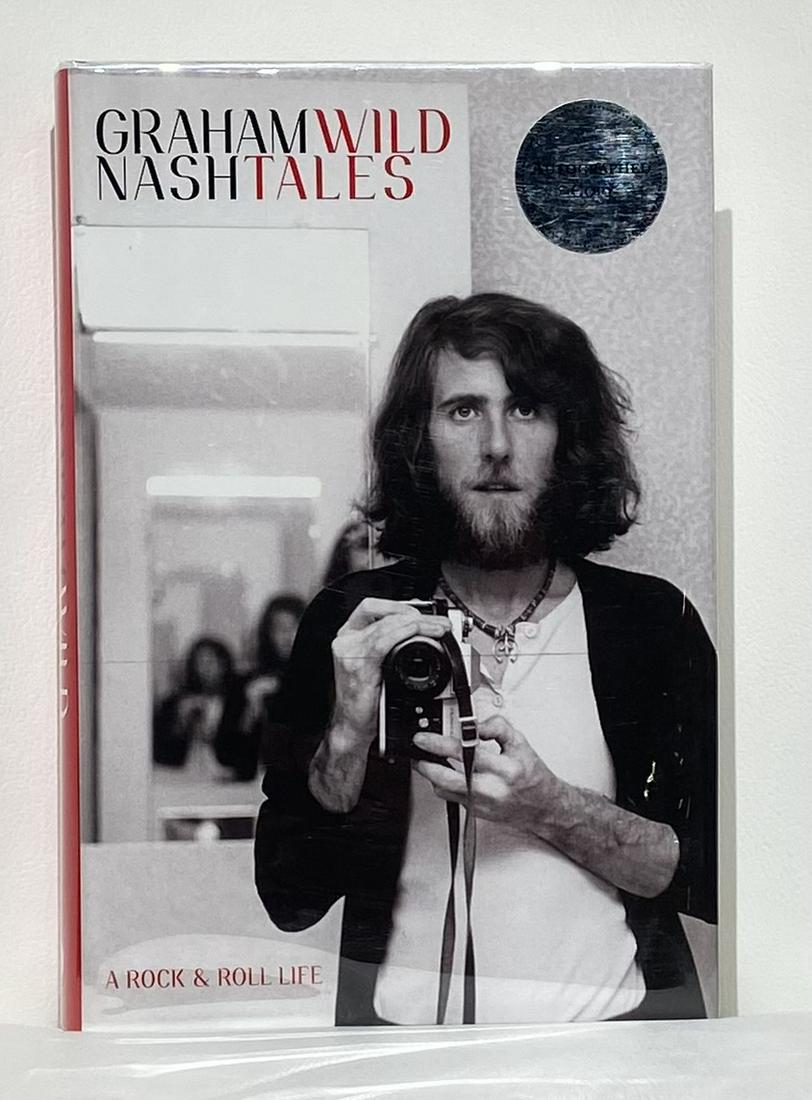 Graham Nash "Wild Tales" Signed Book: Artist: Graham Nash Title: Wild Tales Medium: Book Art Dimensions: 9.5 H x 6.5 W inches Item Description: A candid and riveting autobiography that belongs on the reading list of every
