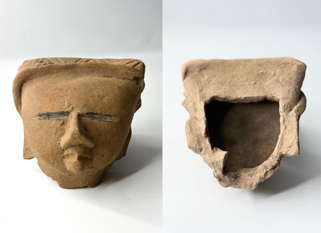 Pre-Columbian Terracotta Head Fragment of a Figure (Possibly Attendant or Deity), Teo: A compelling small-scale Pre-Columbian terracotta head fragment, exemplifying the minimalist yet evocative artistry of ancient Mesoamerican cultures. The face is modeled with serene abstraction: a
