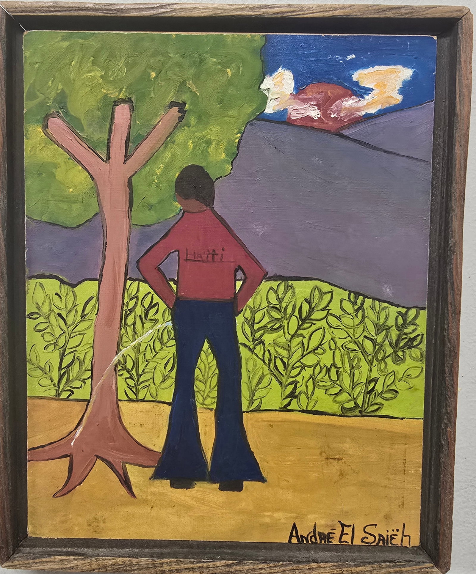 André El Saieh – Figure Contemplating the Haitian Landscape, Bricston Collection: André El SaiehFigure Contemplating the Haitian LandscapeA naïve painting featuring a solitary figure viewed from behind, dressed in a red shirt bearing the word “Haiti” and dark trousers, st
