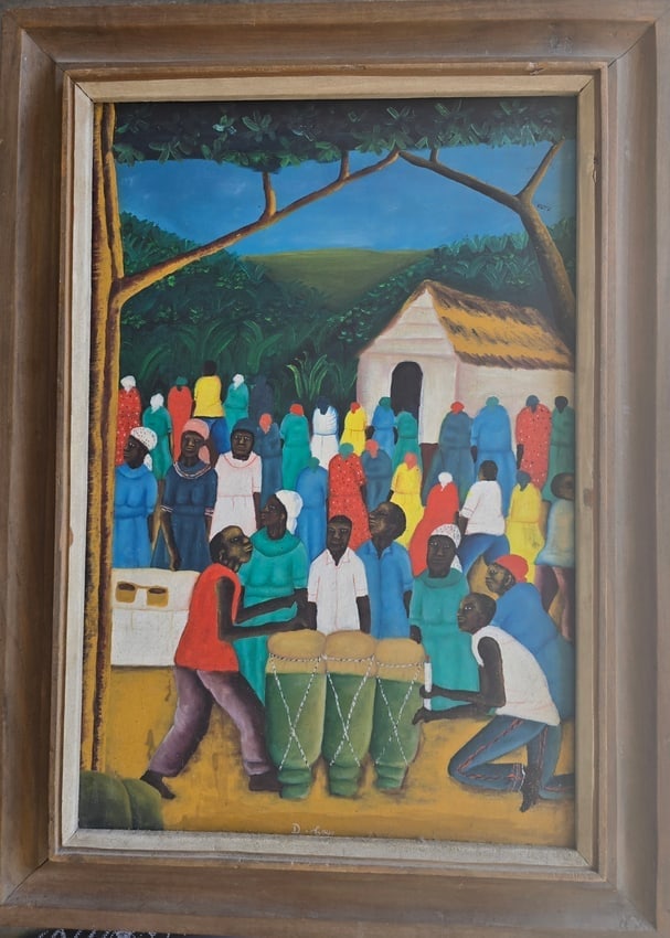 Haitian School (20th C.) Rural Village Celebration with Drummers & Dancers – Ex. Bricston: An energetic, richly populated rural celebration scene rendered in the classic Haitian Naïve tradition. The composition centers on the pulse of communal music, featuring two foreground drummers playi