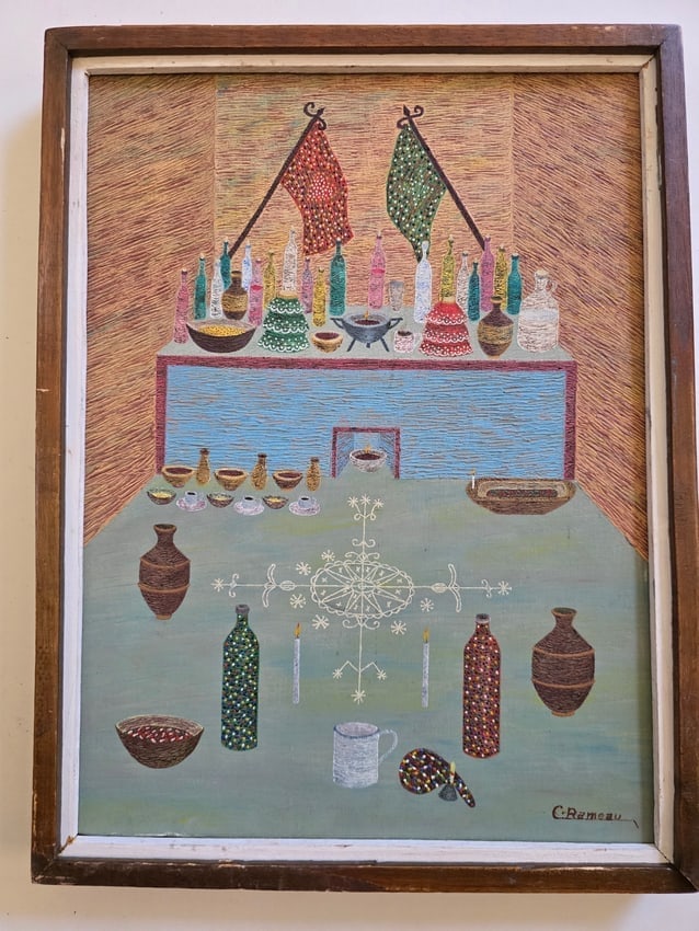 Vodou Altar Still Life by Cameau Rameau: A meticulously detailed, sacred ceremonial still life by listed Haitian master Cameau Rameau (1943–2016). Executed in oil with precision and graphic refinement, the two-tiered composition depicts an