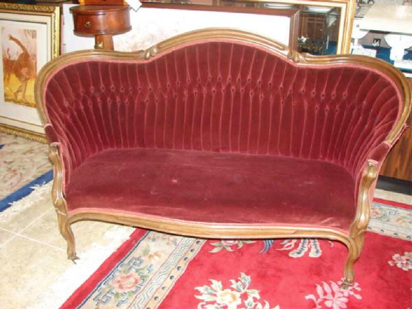 Victorian Style Carved Walnut Settee.: L 67, H - 39" Having serpentine thumb mold crest rail and arms, tufted back, tight upholstered serpentine seat, on casters." Condition, small tear in the seat.