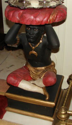 Poly-chromed plaster stand, blackamoor figure.: 20th century reproduction. H - 22.5 inches. Small stand with seated blackamoor figure on plinth base, unknown composition, painted.