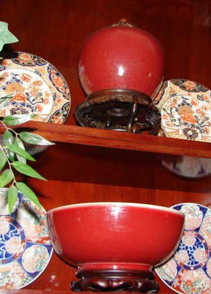 Nine (9) Sang de bouf style glazed pottery items.: Nine (9) Sang de bouf style glazed pottery articles.20th C. reproductions. Pair of covered jars on stand. Two bowls on stands. Covered jar on brass trivet. Two small vases on wood stands. Large flared