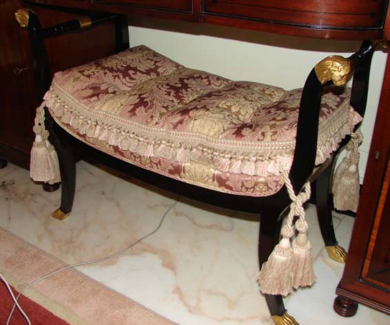 Ebonized wood bench, Georgian style.: Ebonized wood bench, Georgian style.English, 20th C. reproduction. H - 28", L - 36". Gilt and ebonized bench having turned ends with lion head finials, saber legs ending in paw formed feet. Silk jacqu