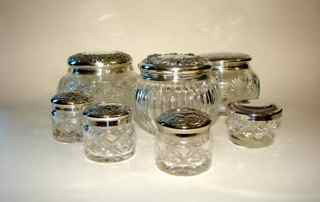 Group of (7) Sterling Silver/Crystal Dresser Jars.: All American, C. 1900. Various makes and patterns, some with monograms, one lid with dents. The three large jars have sterling tops, the four small are silver plated marked Waterford.