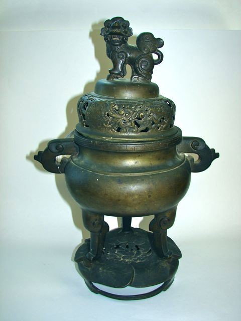 Oriental Bronze Sensor on Stand.: Height - 15.75 inches. Having a foo lion finial pierced lid covering a ovoid footed body with stylized scroll handles, on a lotus form base. Chopmark seal.