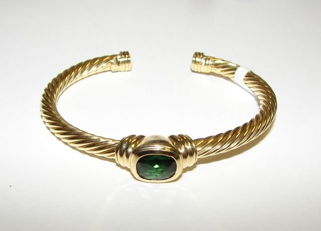 David Yurman 18K Yellow Gold Bangle Bracelet.: 22.4 grams total weight. The bangle in cable twist form with central bezel set green tourmaline oval cut stone, approximately 2 carats in size. Marked David Yurman, 18K". [26]