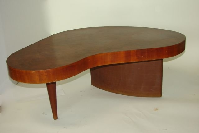 Gilbert Rohde "Paldao" Coffee Table. # 4186.: Made for Herman Miller, nicely veneered bio-morphic top supported on one tapered leg and one curved leg, both legs covered in tan leather. The model # 4186 is stenciled on the bottom. H - 15.5", L - 4