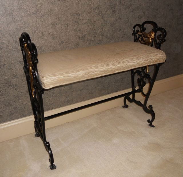 Cast Iron Bench.: L - 25". Painted black with musical Putti's pad cushion seat.