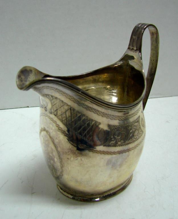Antique English Sterling Cream Pitcher. C. 1727: 2.9 troy ounces. Having the London hallmark crowned lion, lion passant and shielded "L". Scroll and latticed etched banding. Condition: the silver is split on the bottom seam, minor dents. Height 3.25