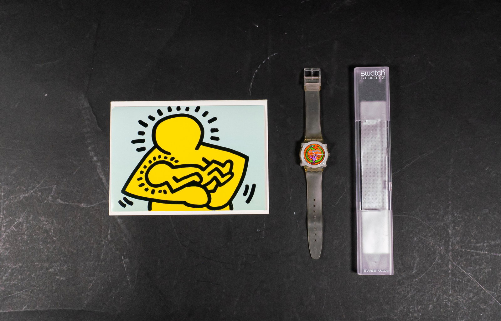 Keith Haring Swatch Watch and Postcard: Swatch watch "Serpent Vert" in transparent resin, water resistant with quartz movement 1985-1986 with original manual and box. 9" L. "Mother and Child" postcard, circa 1985. 5" x 7".