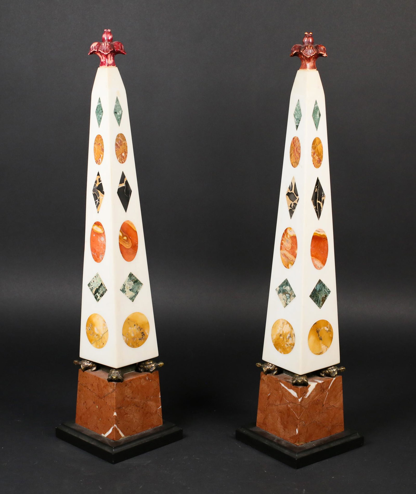 Pair of Continental Marble Obelisks: Pair of continental marble obelisks. Colored marble insets, four turtle form supports. Repair to 1 finial. 2 chips to bottom of 1 obelisk. 22" H.