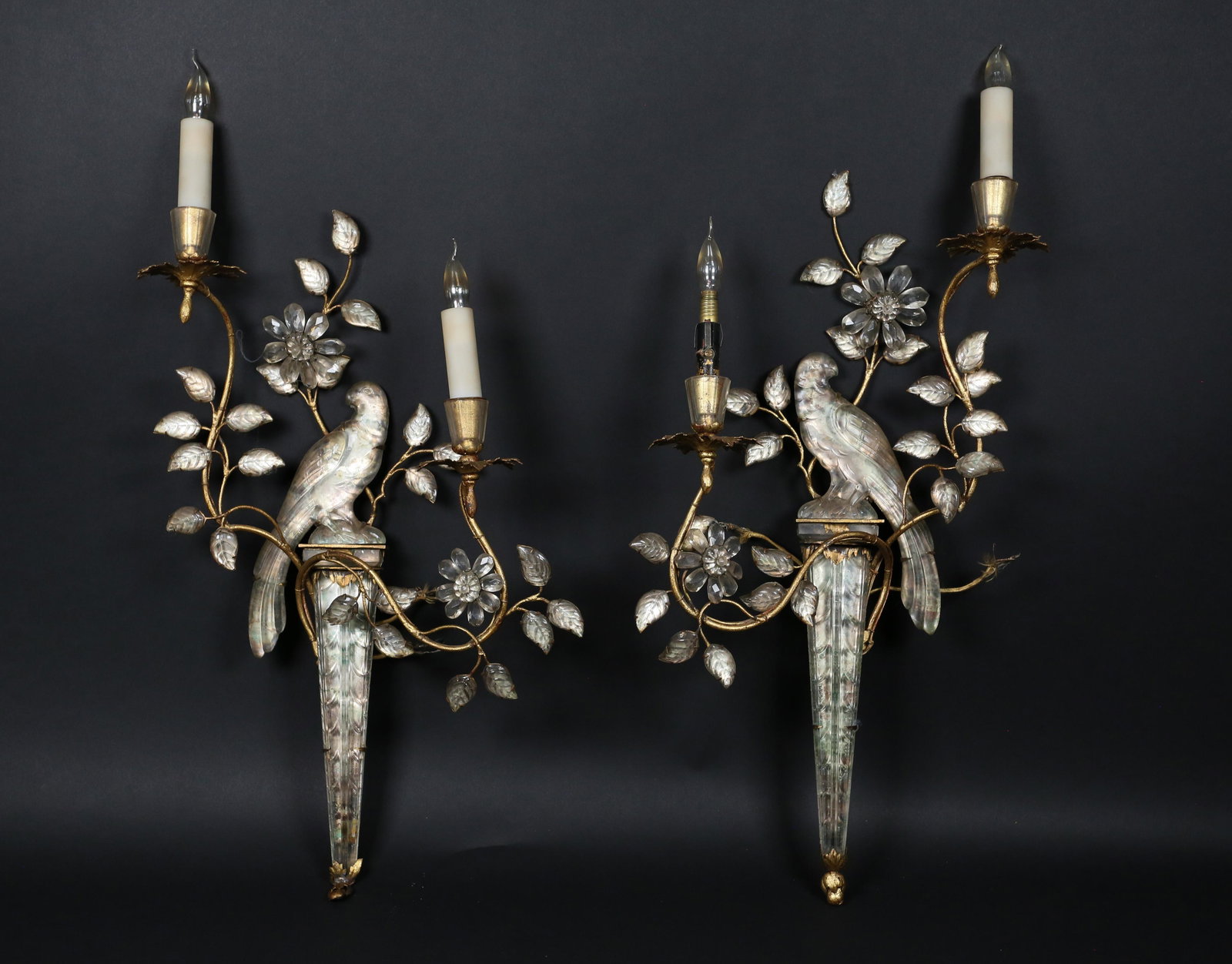 Pair of Maison Bagues Crystal Parrot Wall Sconces: Pair of Maison Bagues gilt metal and rock crystal parrot wall sconces. Flowering vines supporting two candle arms, 2 lights. 1 light missing glass cover, 1 cover with large chip. Wear to gilt. 1 wall