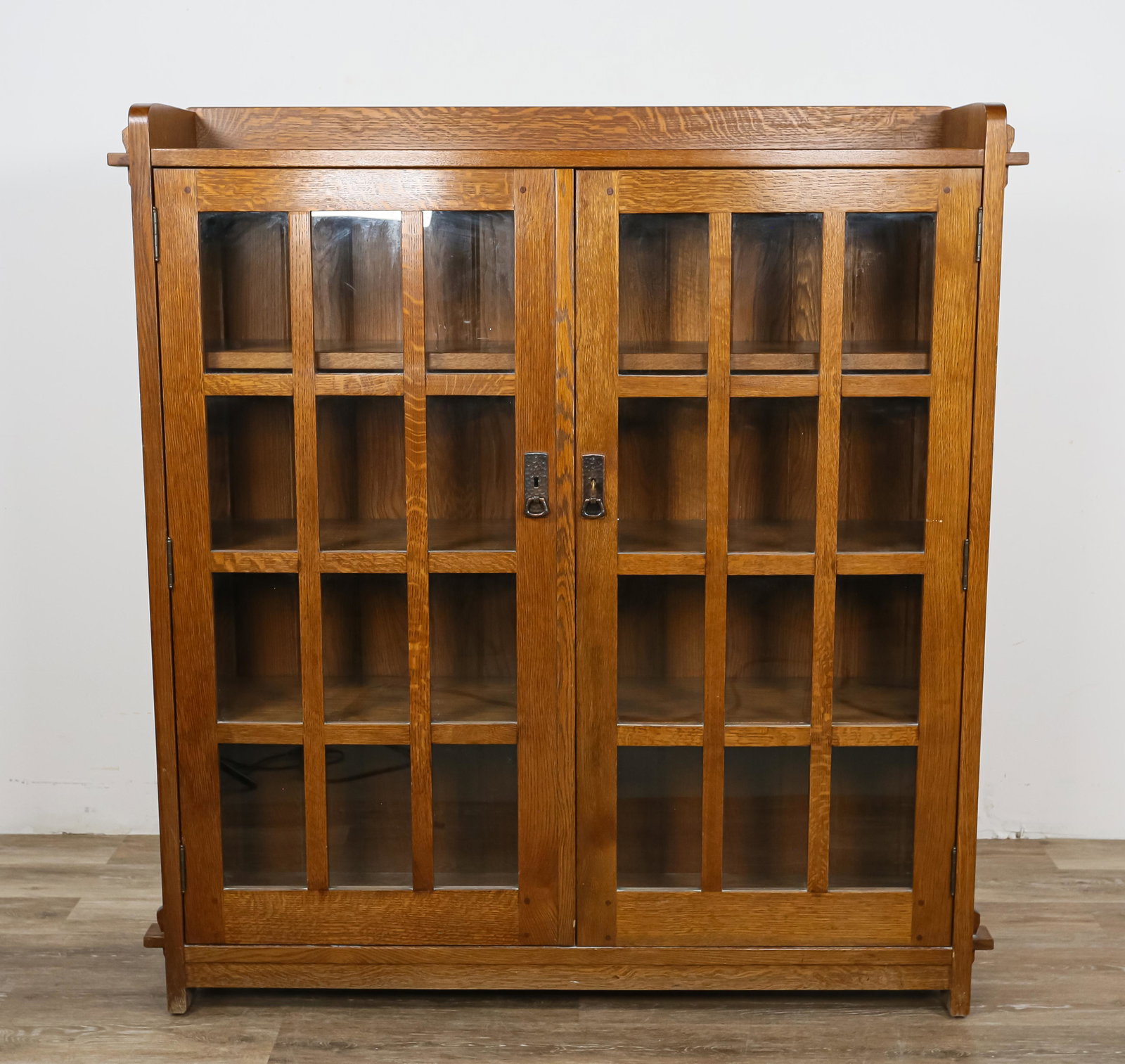 L. & J.G. Stickley Audi Two Door Bookcase: L. & J.G. Stickley / E.J. Audi (1974-). Two door quarter sawn oak bookcase. Through tenons and hammered copper hardware with key. Marked with round metal tag. Water stains to top. 55" H x 49" L x 12" 