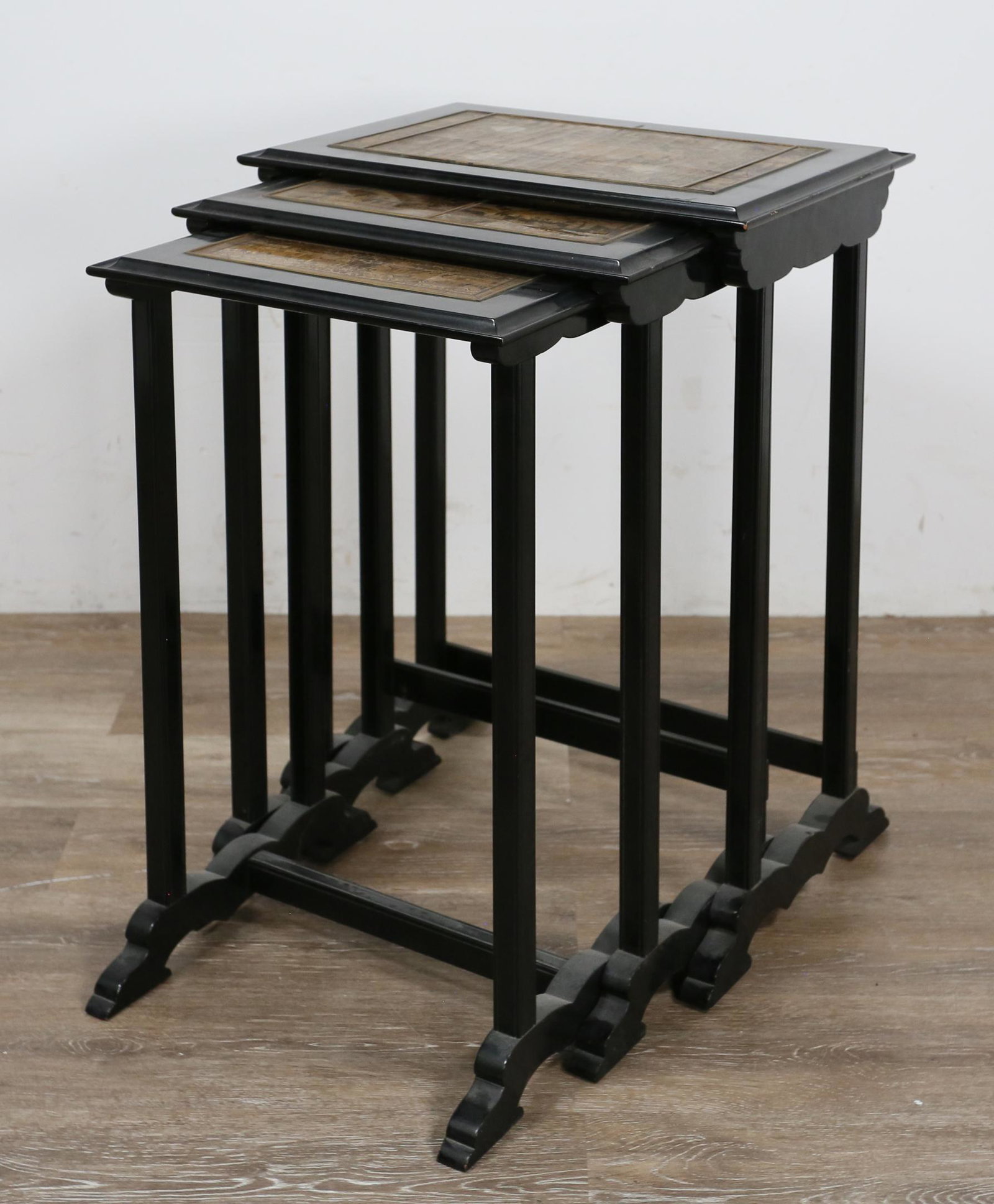 Chinoiserie Nesting Tables: Chinoiserie nesting tables. 20th Century. Lacquered wood with inlaid lacquer and gilt Chinoiserie scenes. Wear to tops, splitting to inlay on largest table. Some slight splitting to other inlaid tops.