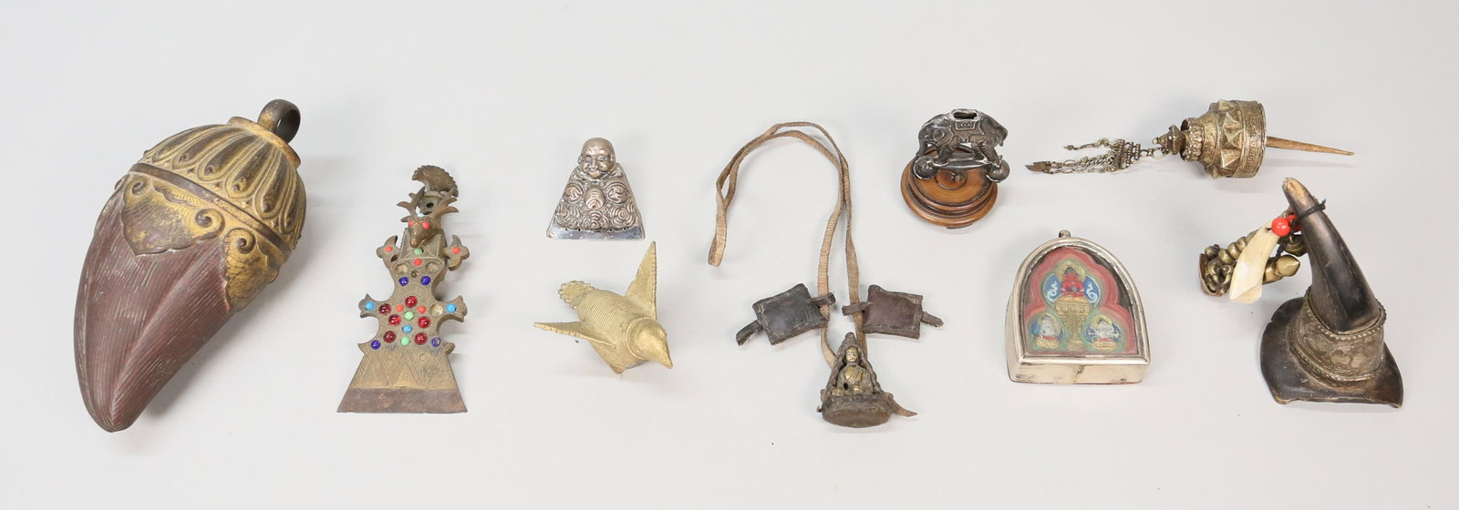 Grouping Of Asian Religious Articles: Two temple toys, one brass bird & one silver tone elephant. Mounted horn with brass decorations. Silvertone Hotei. Bronze hair piece deer motif and colored stones. Leather necklace with seated Buddha.