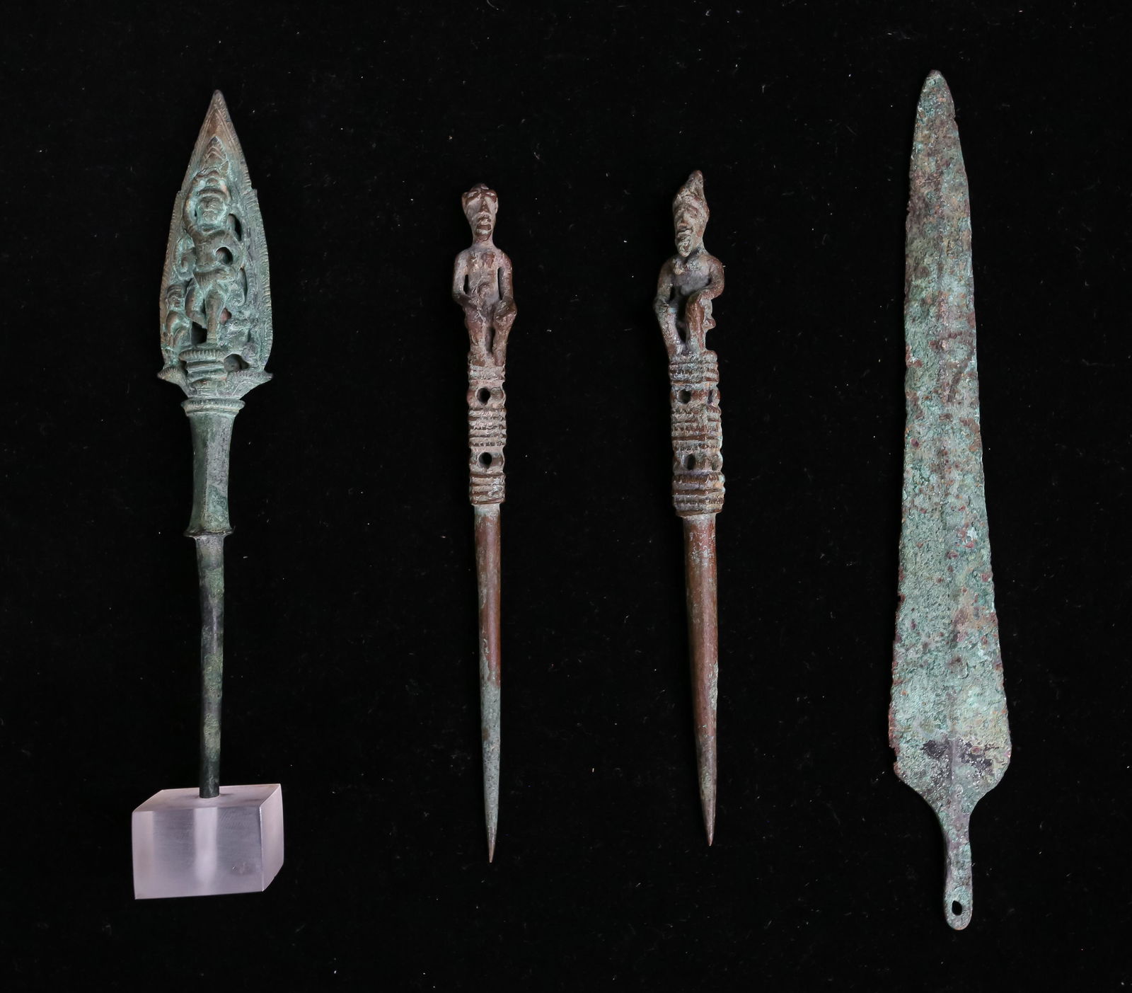 4 Patinated Bronze Items: 4 patinated bronze items. 1 blade, 2 figural pins and a Buddhist arrow point. Blade: 8" L. Buddhist spear point (in Lucite stand): 7 1/4" H.