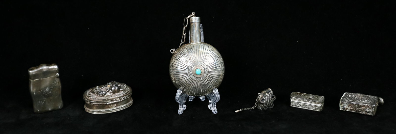 Grouping of Silver Containers: Grouping of 6 silver containers. Snuff bottle with blue stones, elephant pill box, cougar head charm, Islamic pendant with bells, match safe with mermaid and dolphin and a small pill box decorated wit