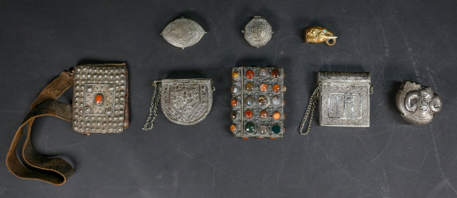 Grouping of Middle Eastern Metal Objects: Grouping of Middle Eastern/ North African metal objects. 2 Islamic pendants with calligraphy. Islamic Quran case with pin. Yemeni style metal case with pin. Moroccan Berber leather purse with carnelia