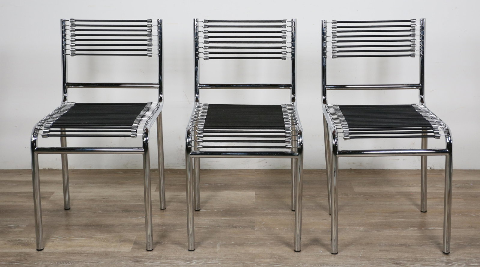 Three Rene Herbst Style Sandow Chairs: Three "101" sandow chairs in the manner of Rene Herbst (French, 1891-1982). Chrome tubular steel and black elastic bungee style cords. Light pilling to some cords. 31 1/2" H x 17" L x 16" W