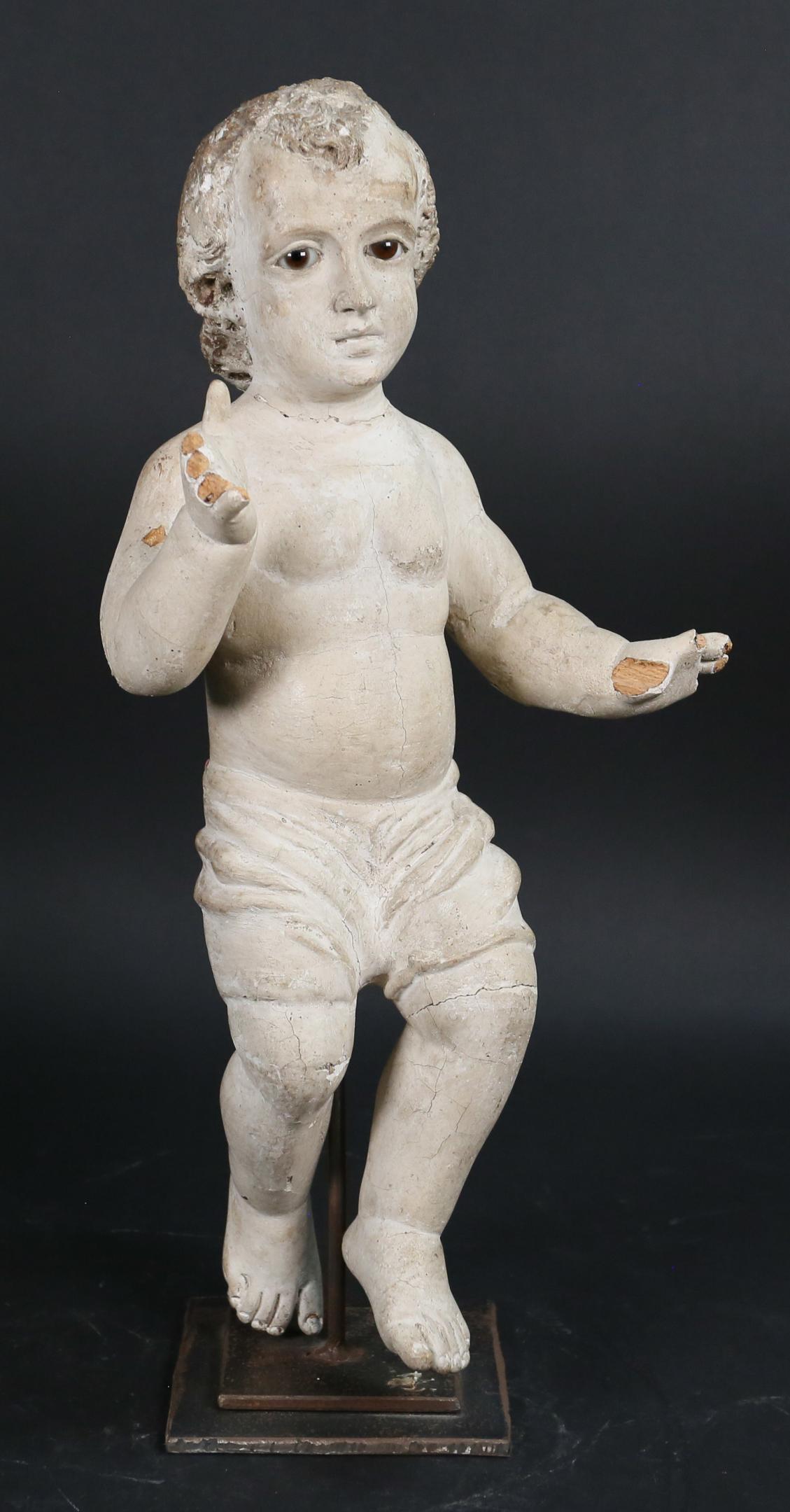 Wood Carved Putti: Wood carved putti on metal stand. Painted, glass eyes. 17 1/2"H including stand (putti approximately 17"H). Paint loss throughout, missing 4 fingers on one hand and 5 fingers on other hand, cracks to