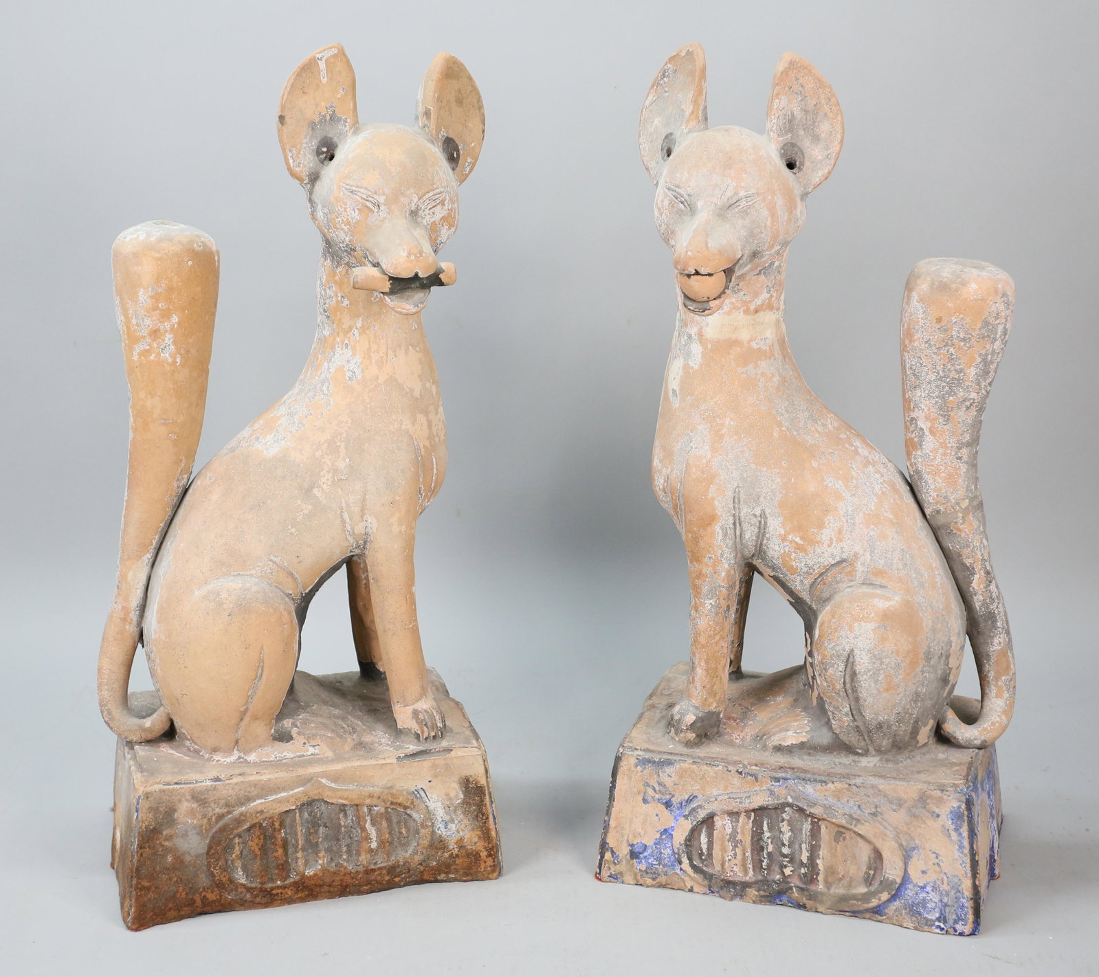 Pair of Japanese Kitsune Fox Temple Guards: Pair of Japanese Inari fox terra cotta pottery temple guards. Each 21 3/4"H x 9 3/4"L x 7 1/4"W. Some paint decoration and paint loss throughout both, chips along bottom edge of bases of both.