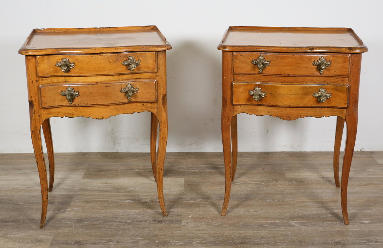 Pair of French Provincial Nightstands: Pair of French Provincial nightstands. Fruitwood and brass drawer pulls. Portion of gallery missing from one nightstand. Scratches and marks to tops and fronts of both nightstands. Marks and indentati