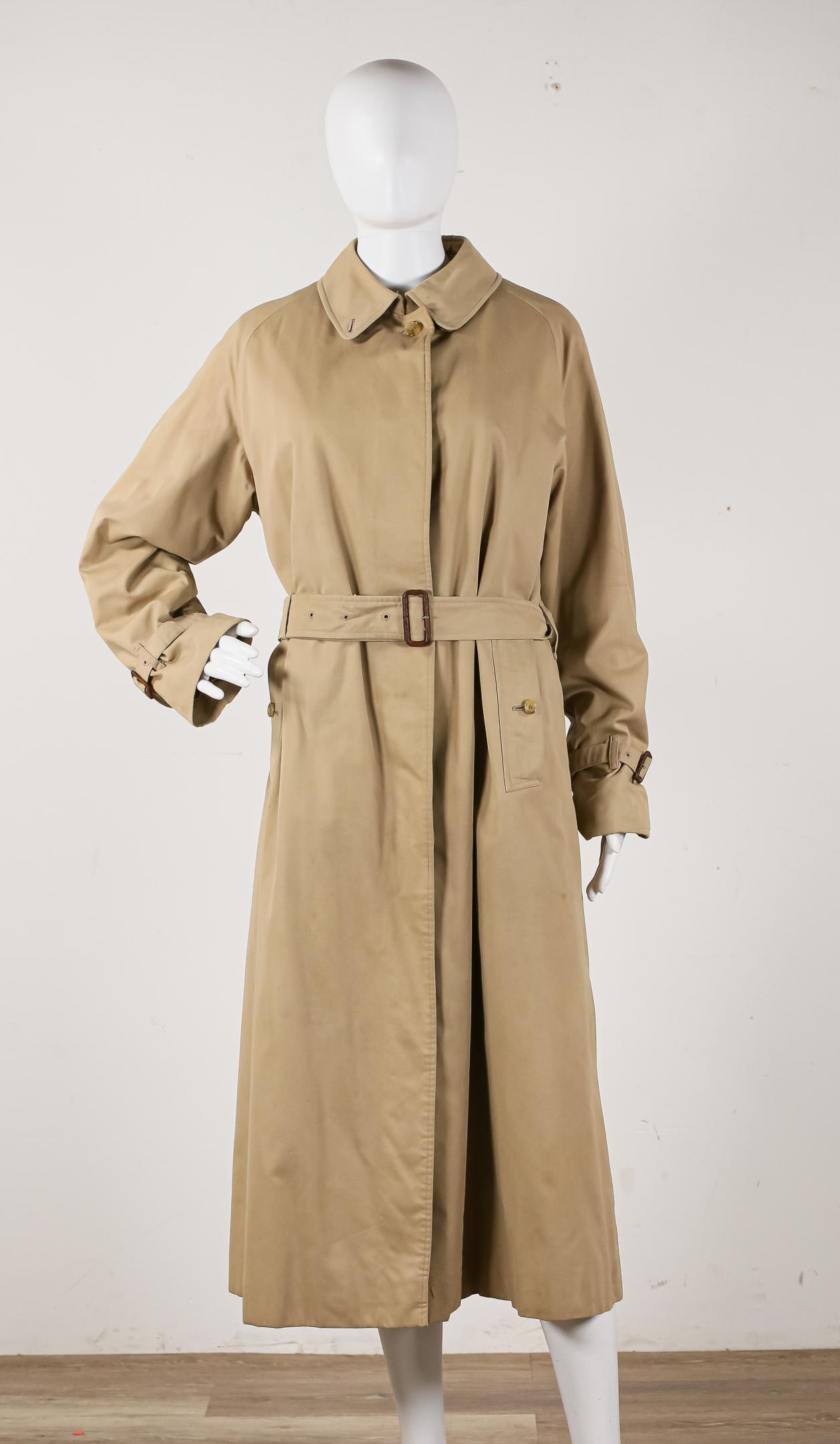 Burberrys Ladies Trench Coat: Classic trench coat from Burberrys, 100% wool, made in England, zip out iconic house check pattern lining, knee length, slit pockets, button closure, minor marks from wear and use, good conditionName