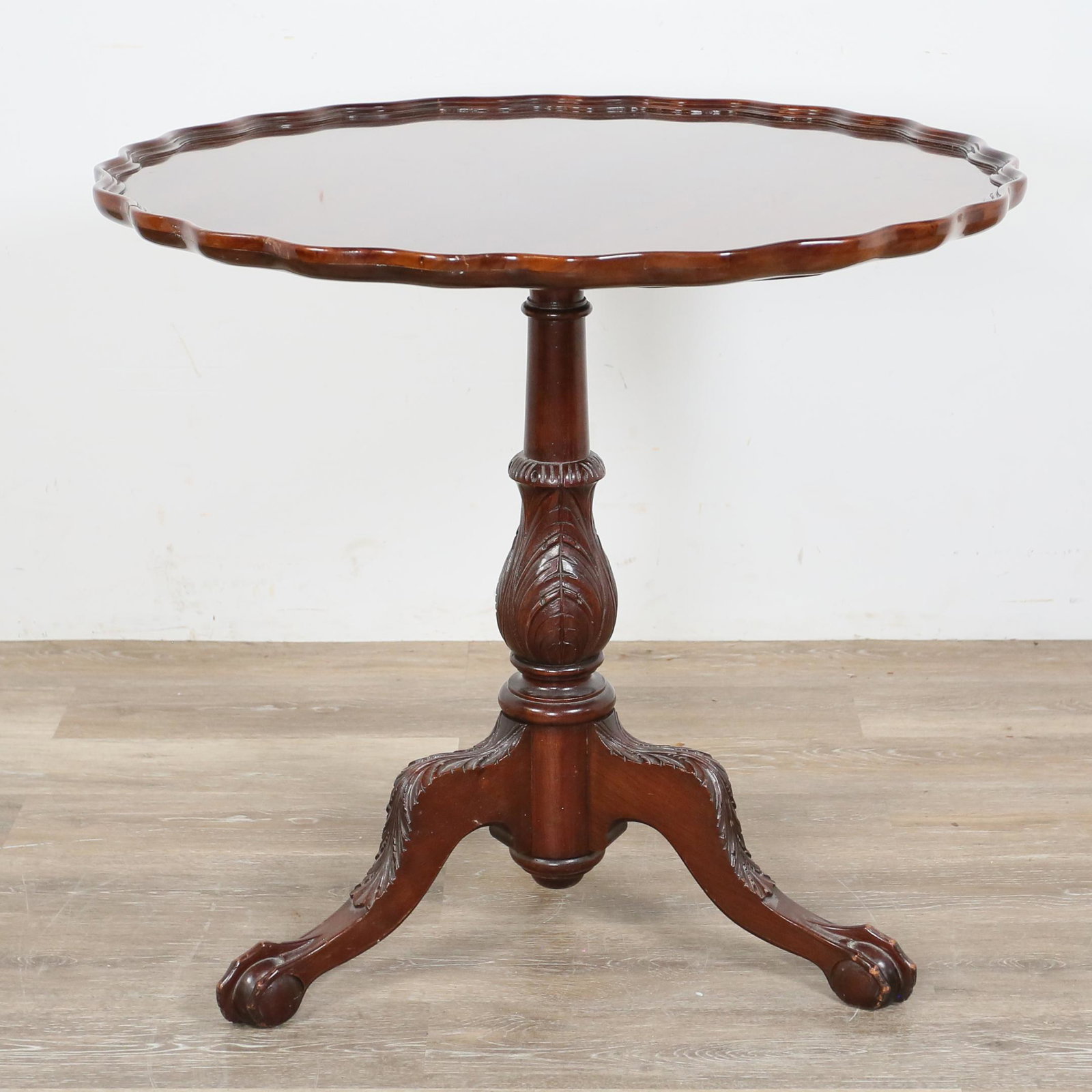 Chippendale Style Pie Crust Tilt Top Table: Chippendale style pie crust tilt top table. 20th century. Mahogany, acanthus leaf motif, ball and claw feet. Light pitting and scratches to top. Indentations to claws of feet. Titled height of 46" Low
