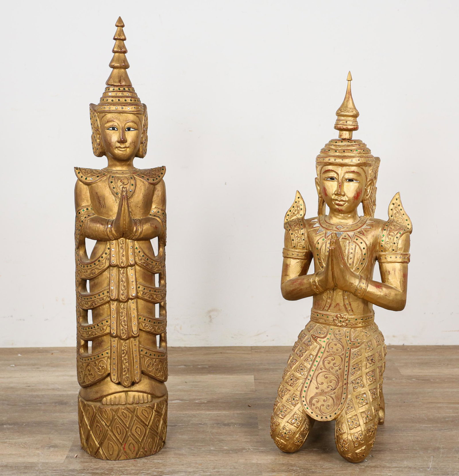 2 Thai Gilt Wood Temple Guardian Statues: 2 Thai gilt wood temple guardian statues. 20th Century. One in kneeling "Thepphanom" pose, other standing straight with hands in prayer. Carved gilt wood inset with glass stones. Wear throughout both 
