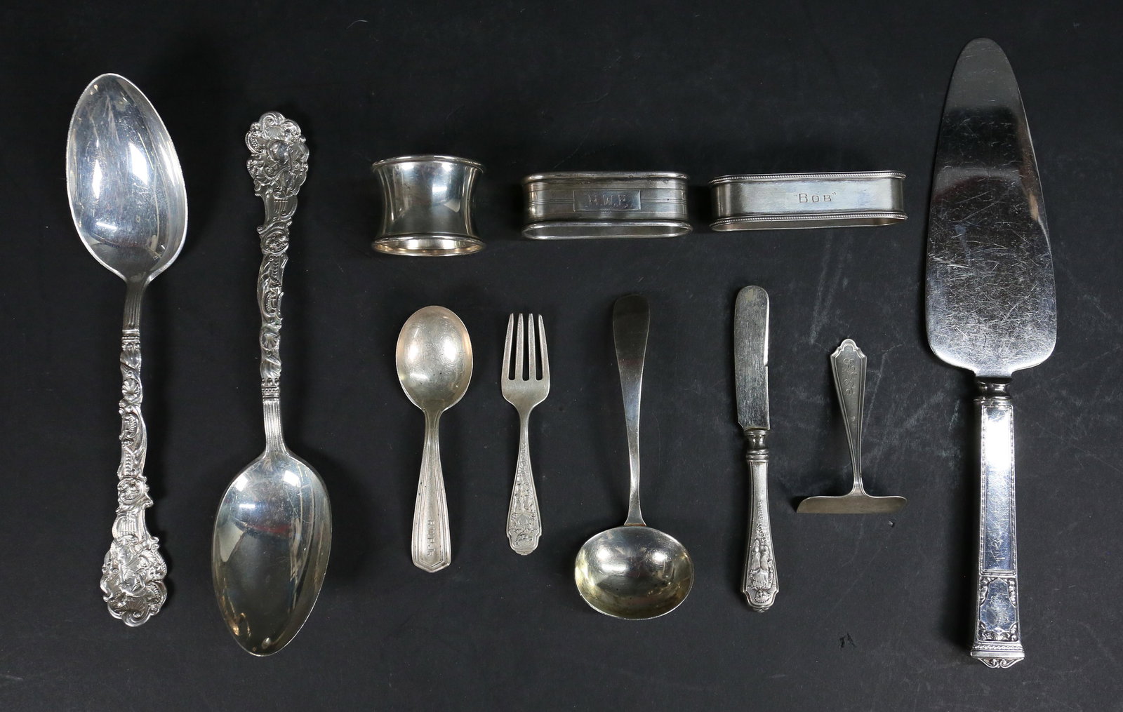 11 Pieces Sterling Tableware: 11 pieces mixed sterling silver flatware and napkin rings. Pair of Gorham Versailles pattern serving spoons, Webster Teddy Bear 2 piece baby set, baby food pusher, small ladle, monogrammed spoon, 3 mo