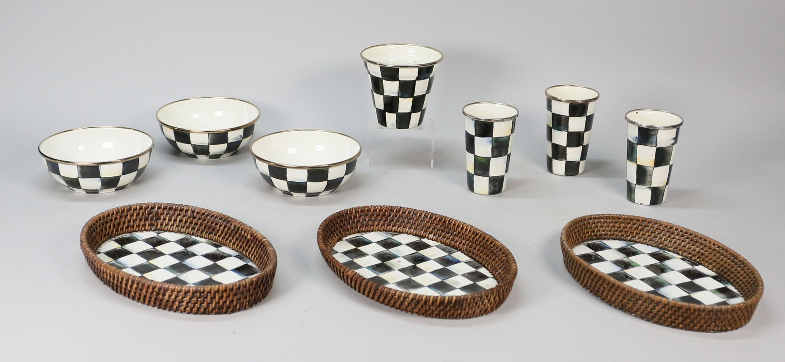 10 Pieces Mackenzie-Childs Courtly Check Enamel: Mackenzie-Childs (American, New York, 1983-). 10 pieces of Courtly Check pattern painted enamel tableware. 3 bowls, 3 tumblers, 3 rattan trays, flower pot. Bowls each 2 1/4"H x 6"-diameter, trays 10 3