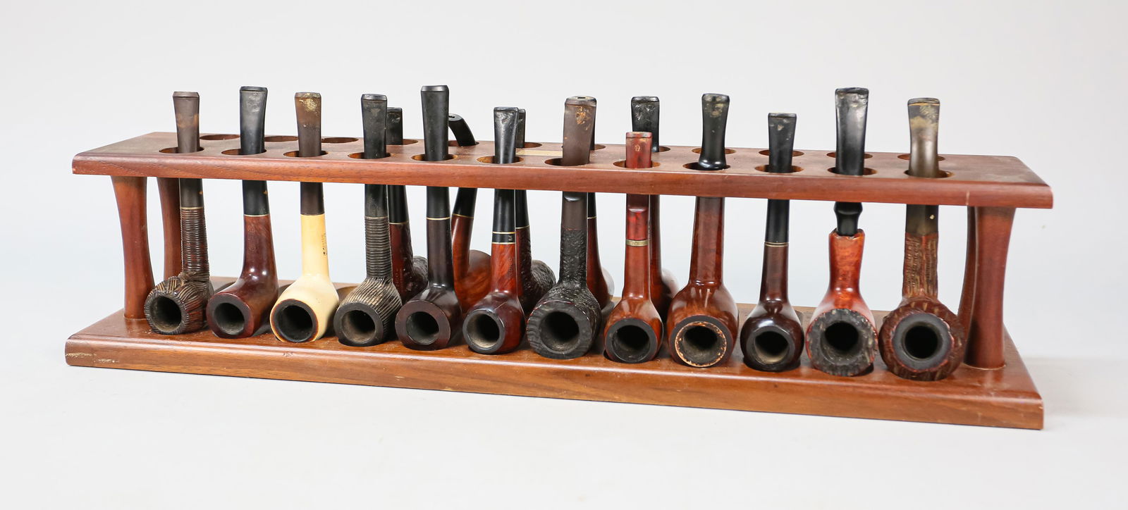 17 Vintage Tobacco Pipes And Pipe Rack: 8 Medico pipes of various shapes. 4 Kaywoodie billiard pipes. 2 Dr. Grabow bent billiard pipes. One marked "Free Hand" and one marked Hillcrest". Jeantet billiard pipe marked "Sir Duke Meerschaum Line