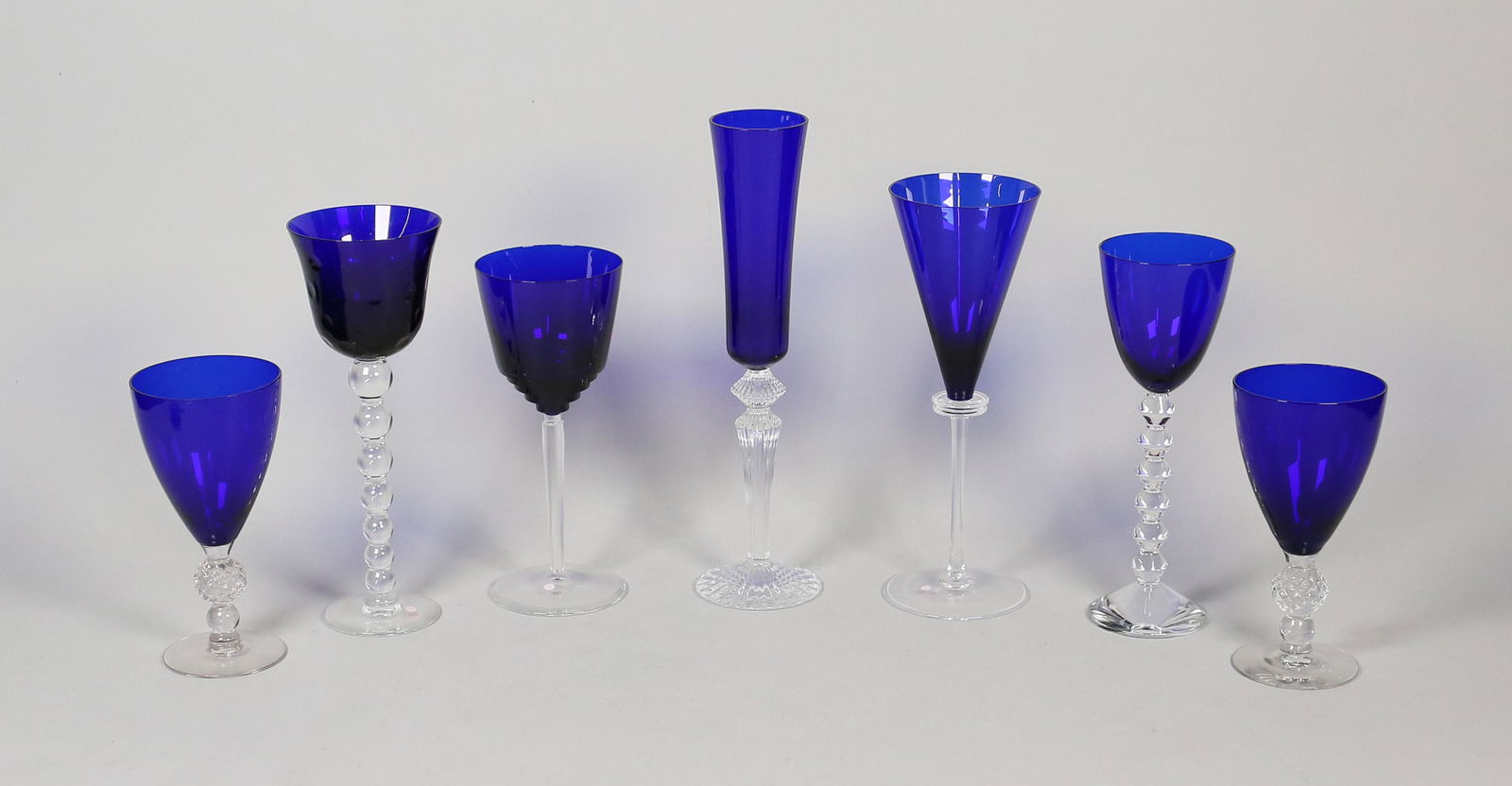 7 Pieces Cobalt to Clear Stemware: 2 Saint Louis, 2 Baccarat - flute signed Mathais, 1 signed illegibly and dated 2003, pair unsigned. Baccarat flute 12"H.