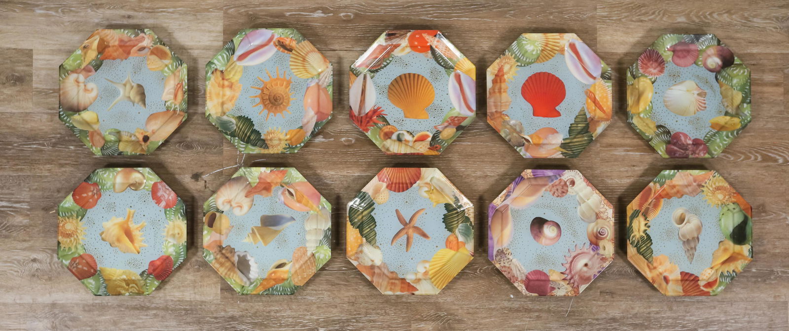 10 Pablo Manzoni Glass Seashell Octagonal Plates: Pablo Manzoni (Italy / American, New York, 1939-2022). 10 octagonal glass plates with collage designs and painted backs. All with seashell motifs on a blue ground. All signed Pablo Manzoni N.Y.C. on t