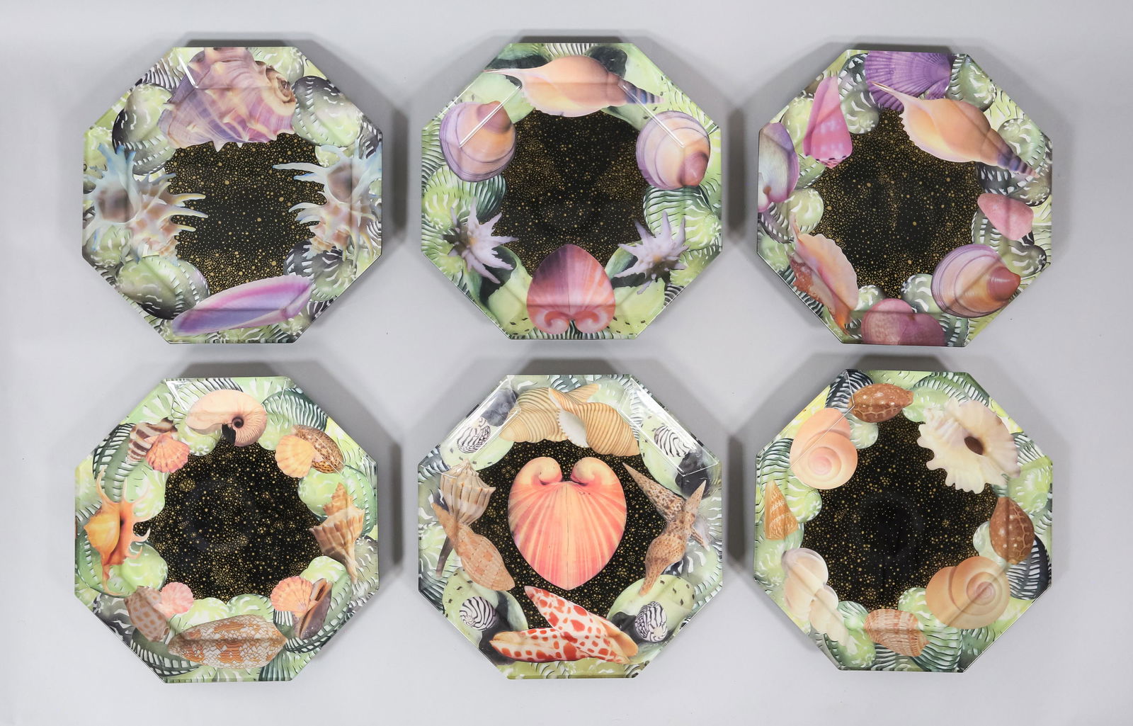 6 Pablo Manzoni Glass Seashell Octagonal Plates: Pablo Manzoni (Italy / American, New York, 1939-2022). 6 octagonal glass plates with collage designs and painted backs. All with seashell motifs on a black ground. All signed Pablo Manzoni N.Y.C. on t