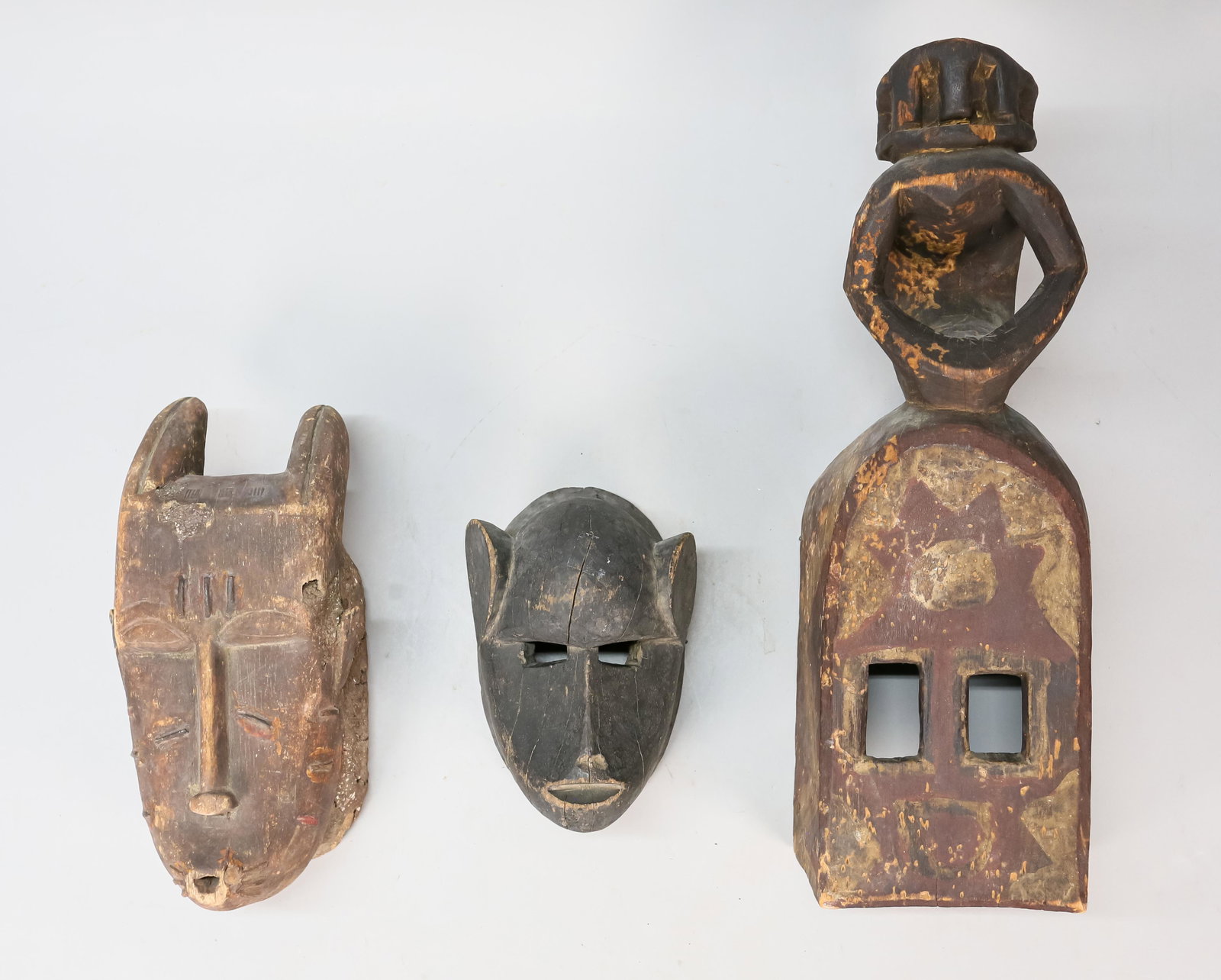 3 African Masks: 3 wood carved masks in the style of the Dogon and Baule peoples of Africa. Dogon mask: 6 1/2" L x 4 1/2" D x 20 1/4" H. Loss to paint, wear to wood.
