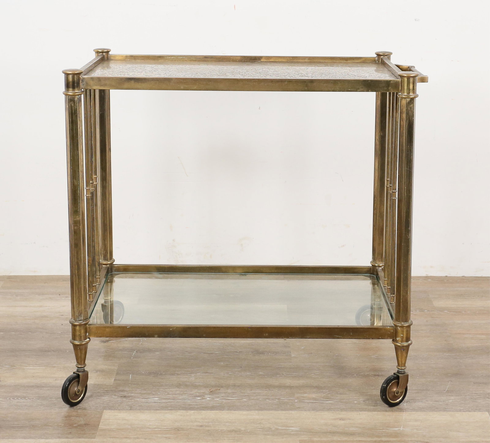 Hollywood Regency Style Bar Cart: Hollywood Regency style bar cart in the style of Baker, Knapp, and Tubbs. American, 20th century. Metal bar cart with metal inlaid glass top and clear glass lower tier. Oxidization to glass top. Light