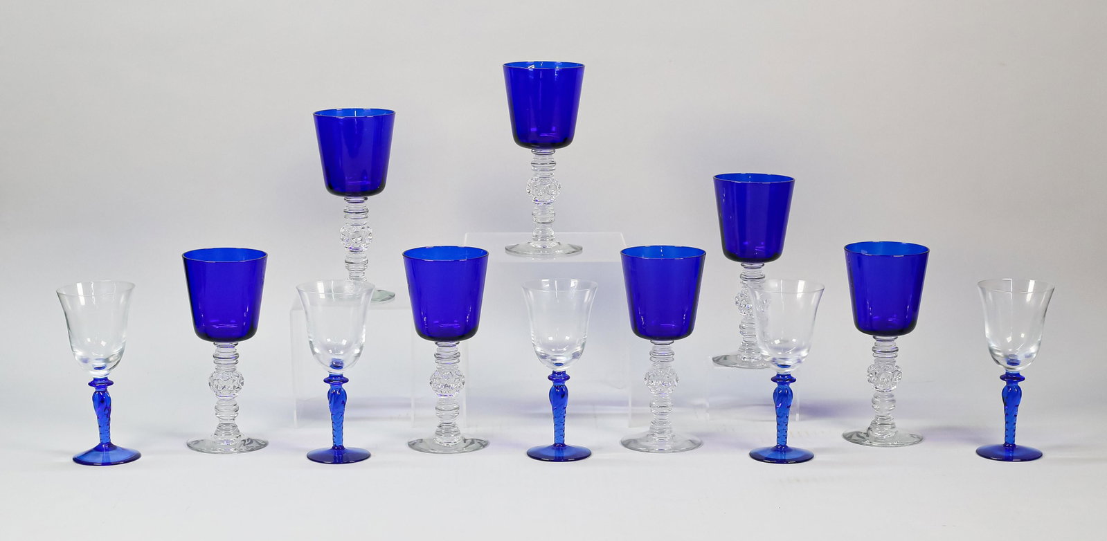 12 Pieces Cobalt to Clear Stemware: 2 sets cobalt to clear glass stemware. Set of 7 Saint Louis style goblets with clear stems and cobalt bowls, each 7 5/8"H; set of 5 wines with cobalt stems and clear bowls, each 6 5/8"H. All unsigned.