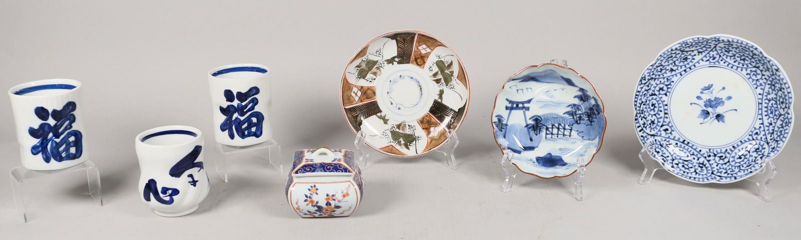 7 Pieces of Japanese Porcelain: 7 pieces of Japanese porcelain. 3 bowls, 1 Sometsuke style, 1 Kutani style and 1 Arita style. 3 tea cups with characters in script. 1 Kozan Gama lidded box, marked on the underside. Chips to brown rim