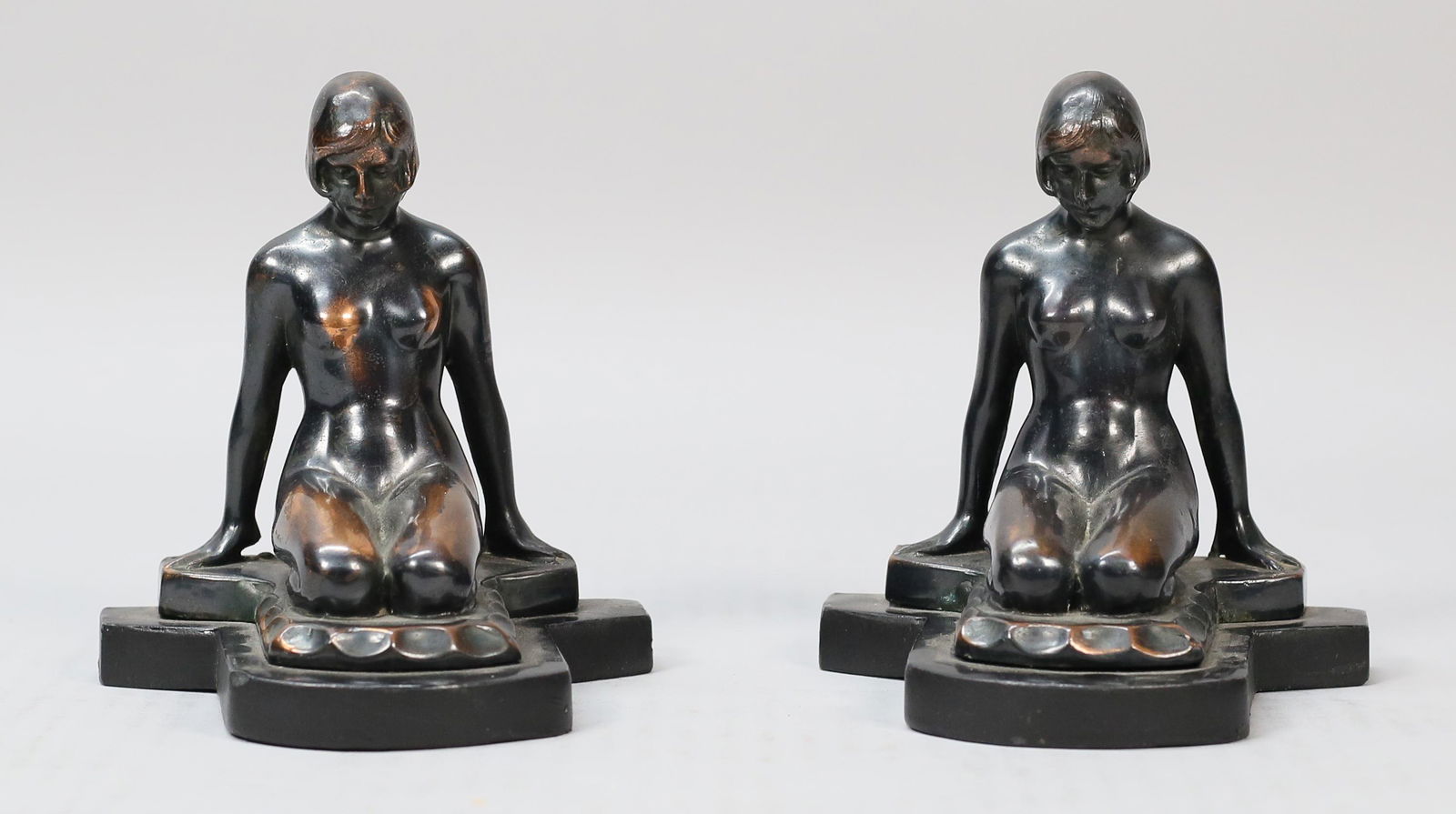 Pair of Art Nouveau Figural Nude Bronze Bookends: Pair of Art Nouveau figural nude bookends. Each depicting nude female kneeling with arms outspread. Copper-tone patina to surfaces of bronze. Pitting and scratches to surfaces of figures. Wear and scu